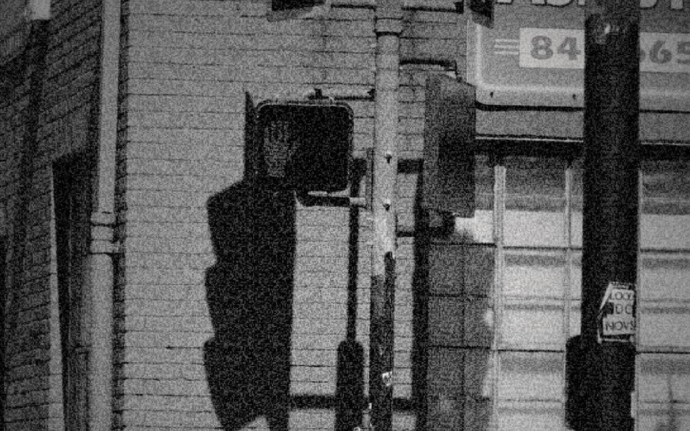 A red brick building with a traffic light and a glowing stop signal, graded as 1930: ortho b and w.