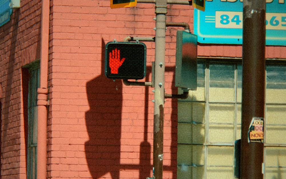A red brick building with a traffic light and a glowing stop signal, graded as 1990: hi8 camcorder.