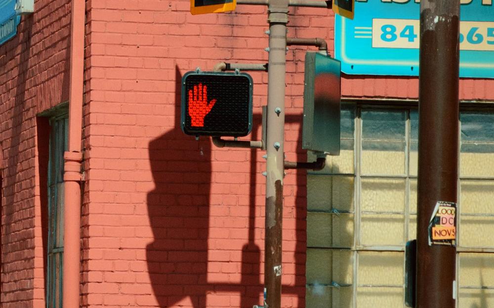 A red brick building with a traffic light and a glowing stop signal, graded as 2020: computational.